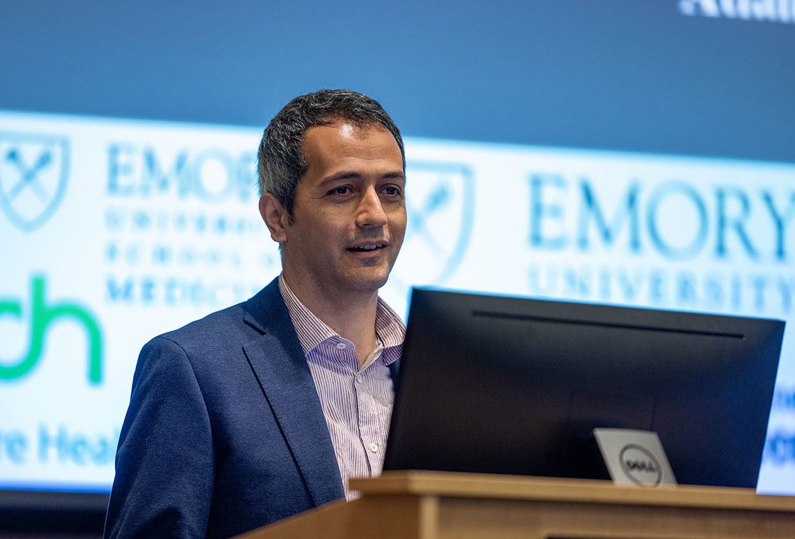 a man in a casual suit speaking at a podium