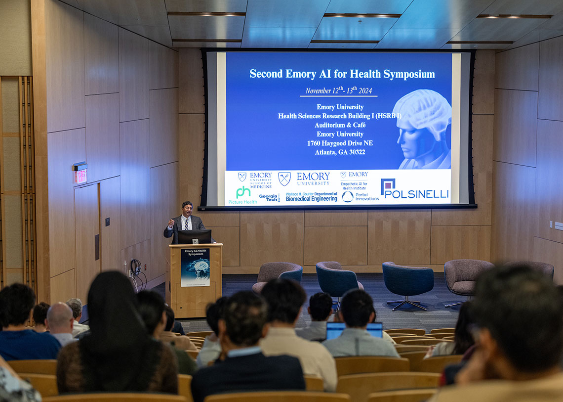 a presentation screen with participant logos and a human brain graphic, being presented in a classroom by Ravi V. Bellamkonda