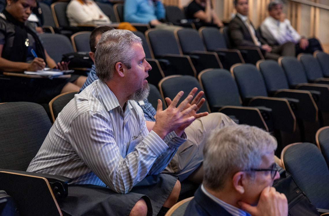 a seated man in the audience leaning forward and engaging in animated conversation